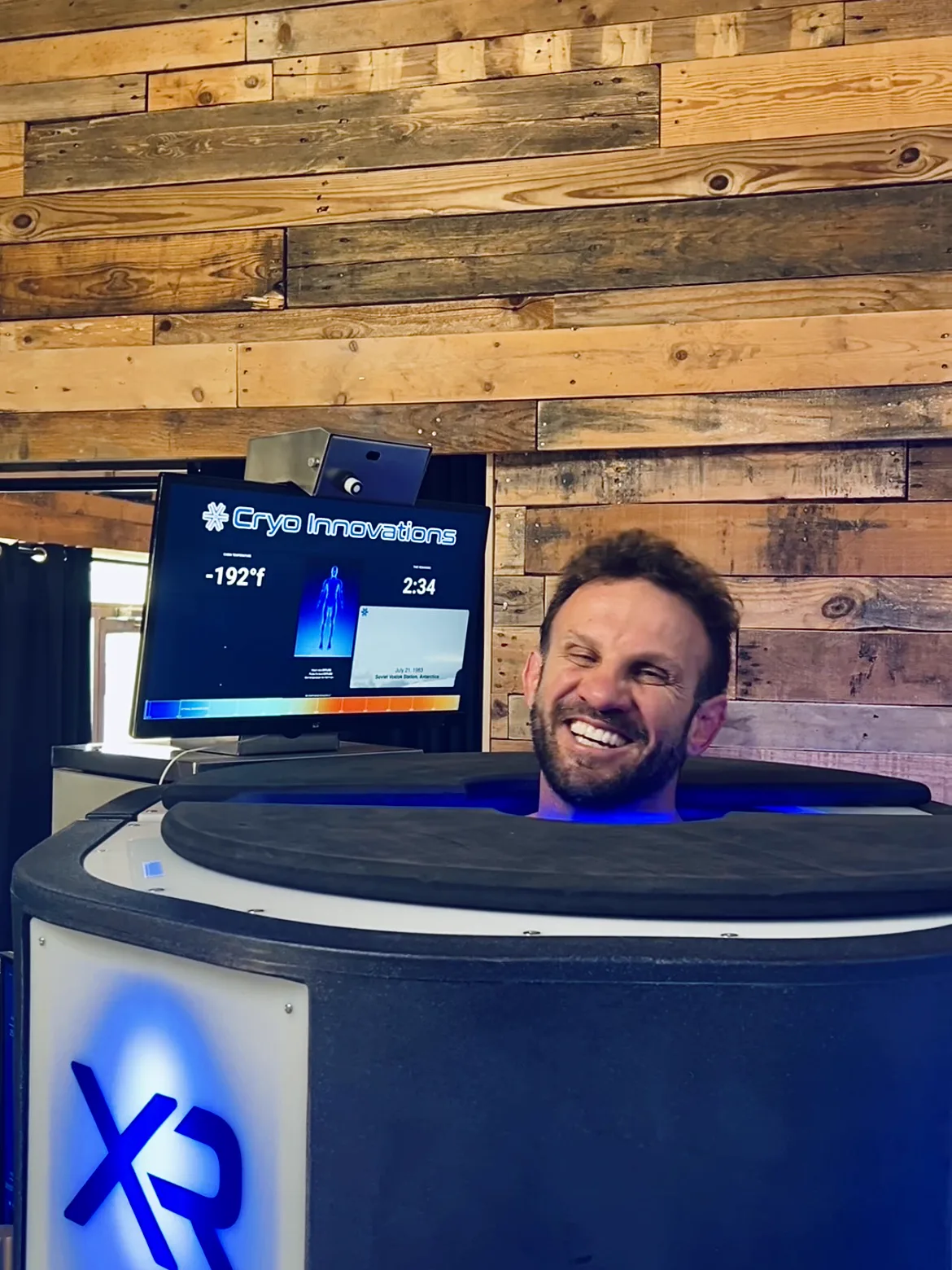 Client smiling mid-session in the XR chamber, cabin display reading -192°F